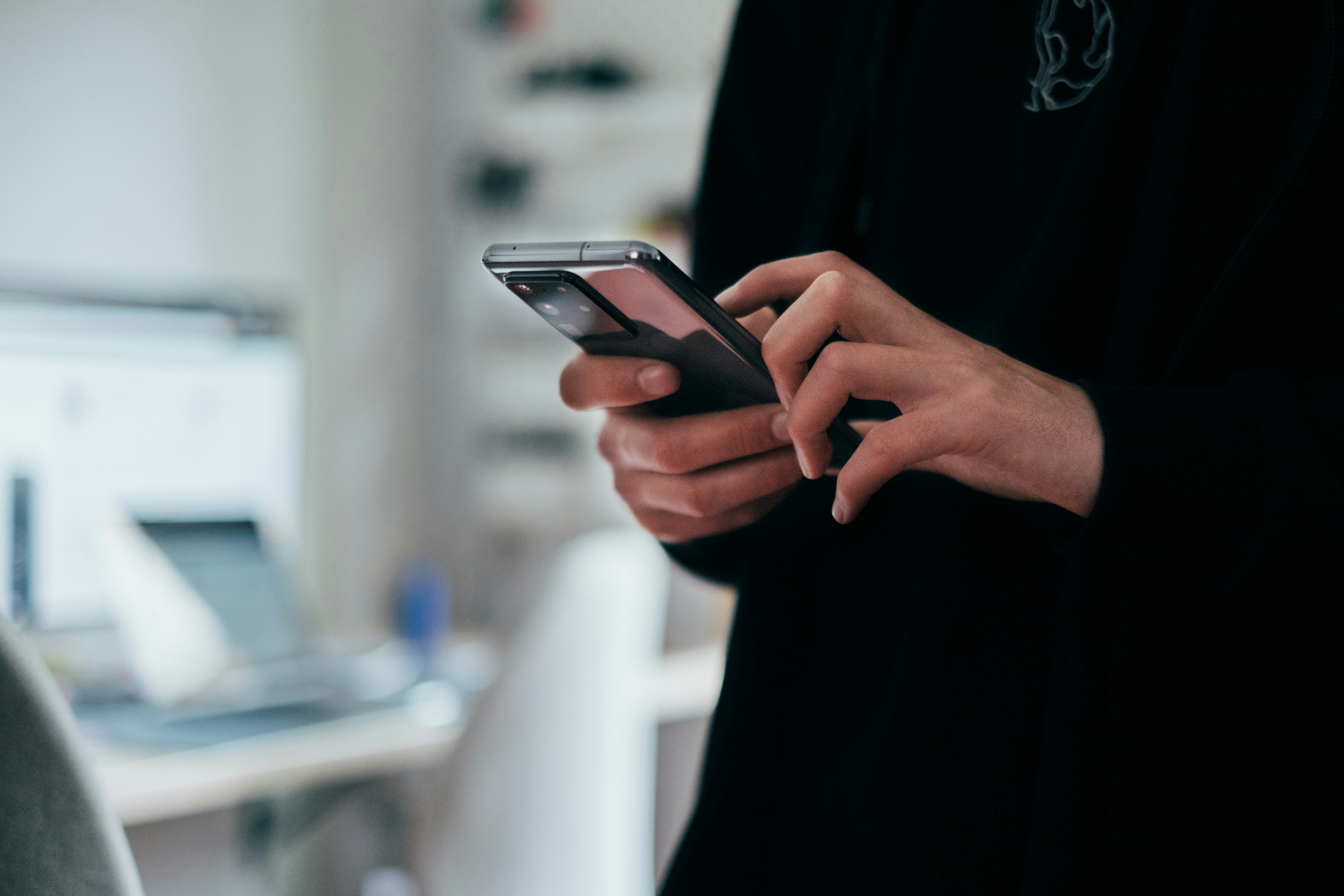 Main tenant un smartphone affichant une application de sécurité domestique